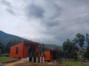 ein kleines orangenes Gebäude mit einem Berg im Hintergrund in der Unterkunft Hospedaje cabaña Guatavita finca las acacias in Guatavita