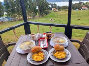 una mesa de madera con platos de comida. en Hospedaje cabaña Guatavita finca las acacias, en Guatavita