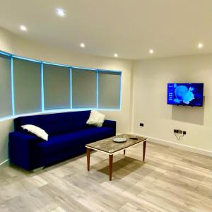 a living room with a blue couch and a table at Comfortable One Bedroom Flat With Car Park In London in London