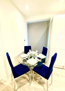 een eetkamer met een glazen tafel en blauwe stoelen bij Comfortable One Bedroom Flat With Car Park In London in Londen