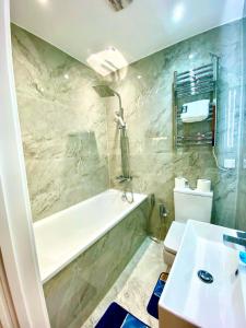 een badkamer met een bad, een toilet en een wastafel bij Comfortable One Bedroom Flat With Car Park In London in Londen