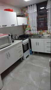 a kitchen with white cabinets and a stove at Casa de 3 Quartos em Garopaba - Bairro Ferraz in Garopaba