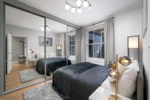 a bedroom with two beds and a large mirror at NIRU Experience Urban Escape 1BR Retreat in London