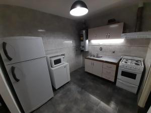a small kitchen with a white refrigerator and a microwave at Sueños del Pilar 1 G Cruz # Casa Dpto # Mendoza # Estacionamiento # Bodegas in Mendoza
