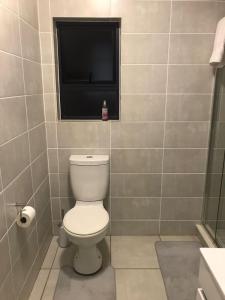 a bathroom with a toilet and a television on the wall at Laguna Getaway at The Blyde in Pretoria