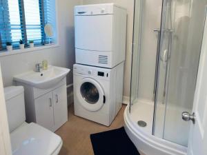 a bathroom with a washing machine next to a washer at Remarkable 3-Bed Ground Floor Apartment - Coventry in Coventry