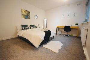 a bedroom with a large bed and a desk at Remarkable 3-Bed Ground Floor Apartment - Coventry in Coventry