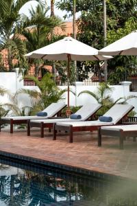 a row of lounge chairs with umbrellas next to a pool at Chic stay HANA Boutique hotel in Luang Prabang