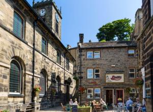 un edificio con una torre de reloj y gente sentada en las mesas en Cottage in Holmfirth Centre en Holmfirth