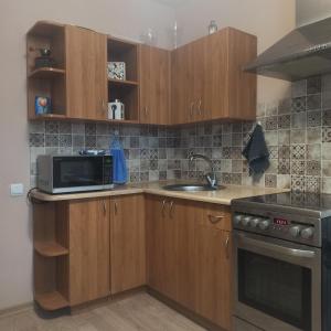 cocina con armarios de madera, fregadero y microondas en Lake apartment, en Visaginas