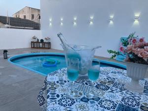 a table with glasses on it next to a swimming pool at H&C Pousada in São Gabriel