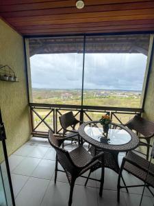 a balcony with a table and chairs and a large window at Hotel Fazenda Monte Castelo Flat Gravatá in Bezerros