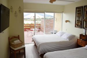 a bedroom with two beds and a balcony with a table at Riomar Apart Hotel in Concón