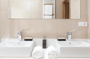 Baño blanco con 2 lavabos y espejo en Aparthotel Jardines de Aristi, en Vitoria-Gasteiz