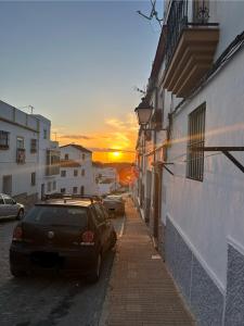 un coche aparcado en una calle con la puesta de sol en el fondo en Vientos de Alcornoque, en Alcalá de los Gazules