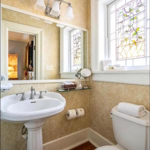 uma casa de banho com um lavatório, um WC e uma janela. em Burke Mansion em Macon
