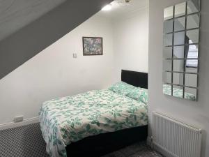 a bedroom with a bed with a green and white comforter at Apartments Azalea Terrace in Sunderland