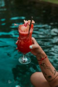 una persona sosteniendo una bebida junto a una piscina en Villa Coco, en Santa Catalina