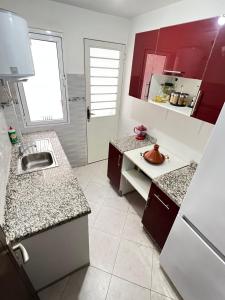 una cocina con encimeras rojas y blancas y fregadero en New apartment, fully equipped, en Ville Nouvelle
