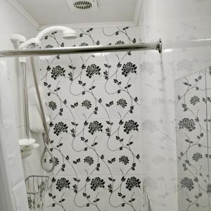 ein Bad mit einem Duschvorhang mit Blumenmuster in der Unterkunft Cosy Rooms near Canary Wharf & the O2 in London