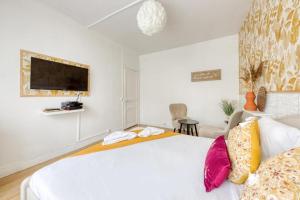 a bedroom with a large white bed with colorful pillows at Studio cosy en centre-ville Proche de Paris in Pierrefitte-sur-Seine