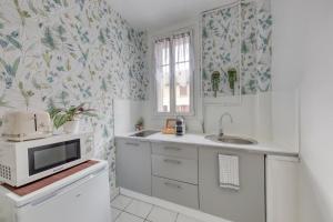 a kitchen with a sink and a microwave at Studio cosy en centre-ville Proche de Paris in Pierrefitte-sur-Seine