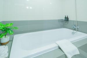 a white bath tub with a towel next to a plant at We Grand Ever 9 in Nakhon Ratchasima +67 photos