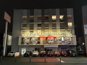 Un edificio con coches aparcados delante por la noche. en Fukuoka Share Hotel, en Fukuoka