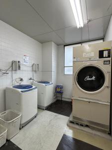uma lavandaria com uma máquina de lavar roupa e um lavatório em Fukuoka Share Hotel em Fukuoka
