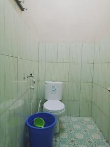 a bathroom with a toilet and a blue bucket at Penginapan Ana Indah in Borobudur +33 photos