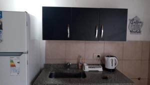 a kitchen counter top with a sink and a refrigerator at La Yuma en Villars in Villars