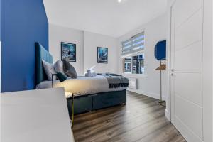 1 dormitorio con cama y pared azul en Lovely Two Bedroom with Ensuite Bathrooms, en Londres
