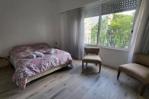 a bedroom with a bed and a chair and a window at Departamento en glamourosa calle, 1 dormitorio in Buenos Aires