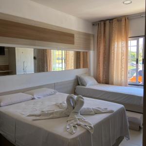 a bedroom with two beds and a mirror at Pousada Residência dos Sonhos in Porto De Galinhas