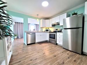 a kitchen with white cabinets and a stainless steel refrigerator at Marsh House, HOT TUB, Waterfront, KING bed, Close to Lejeune, in Cedar Point