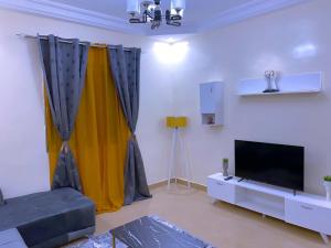a living room with a couch and a flat screen tv at Cosy Appartement Maristes Dakar in Dakar