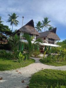 um resort com dois telhados de palha e palmeiras em Private Beachfront Villa in Siargao em General Luna