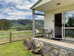 a porch with two chairs and a table on it at Okauia Lodge in Matamata