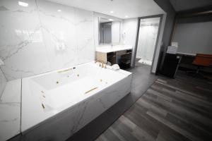 Baño blanco con bañera y lavamanos en Travelodge by Wyndham Whittier en Whittier