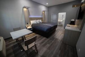 1 dormitorio con cama, mesa y espejo en Travelodge by Wyndham Whittier en Whittier