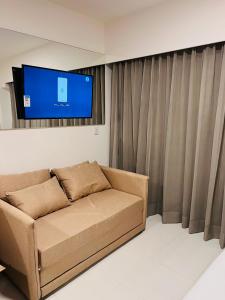 ein Wohnzimmer mit einem Sofa und einem Flachbild-TV in der Unterkunft Makia Beach Experience in Ipojuca