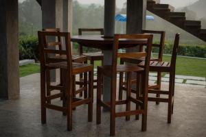 Ceylon Nature Paradise في Uragasmanhandiya: طاولة خشبية بأربعة كراسي وطاولة مع شرفة