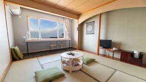 een woonkamer met een groot raam en een tafel bij Hotel Kifu Club Shiretoko in Shari