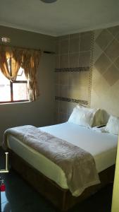 uma cama grande num quarto com uma janela em Legacy Guest Lodge em Joanesburgo