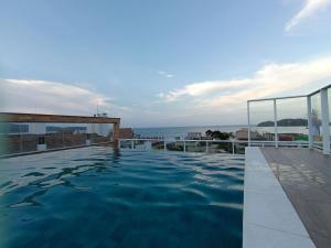 a swimming pool with the ocean in the background at Vila do Centro in Bombinhas