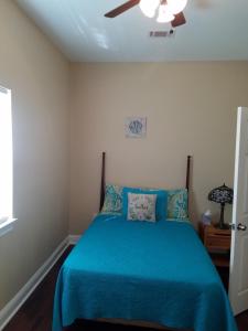 a bedroom with a blue bed with a ceiling fan at Troy's Place in New Orleans