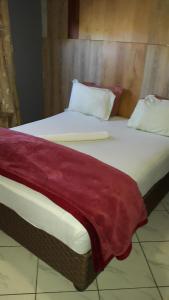 a large bed with a red blanket on it at Legacy Guest Lodge in Johannesburg +15 photos