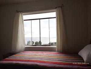 a bedroom with a window and a bed with a colorful blanket at Tukuypaj Amantani in Amantani