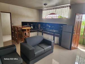 a living room with a couch and a kitchen at Peluza's place in Puerto Jiménez
