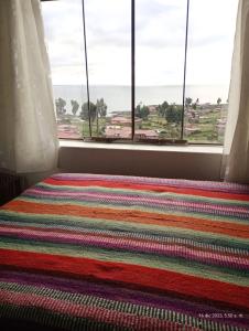 una ventana con una alfombra colorida delante de una ventana en Tukuypaj Amantani en Amantani